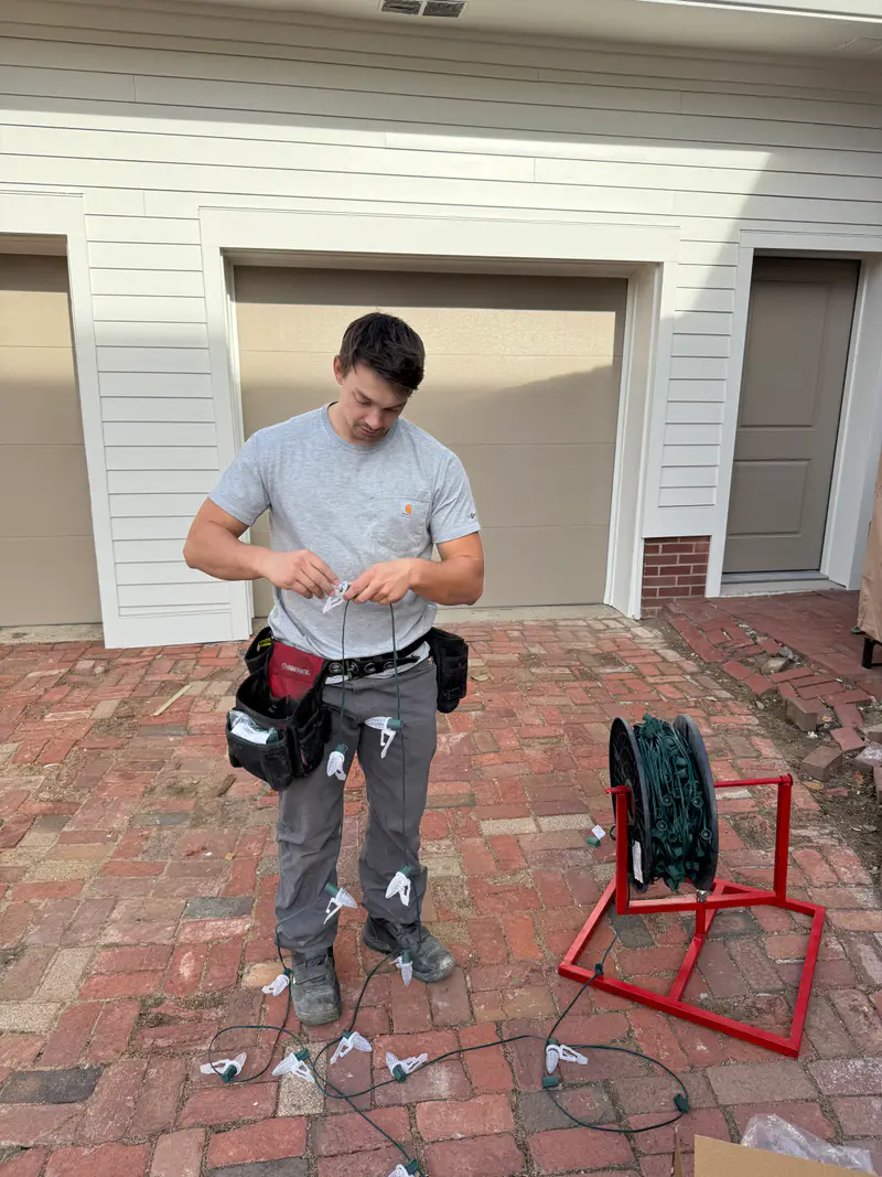 Installer in a tool belt beside a reel of wire on a brick patio before a job