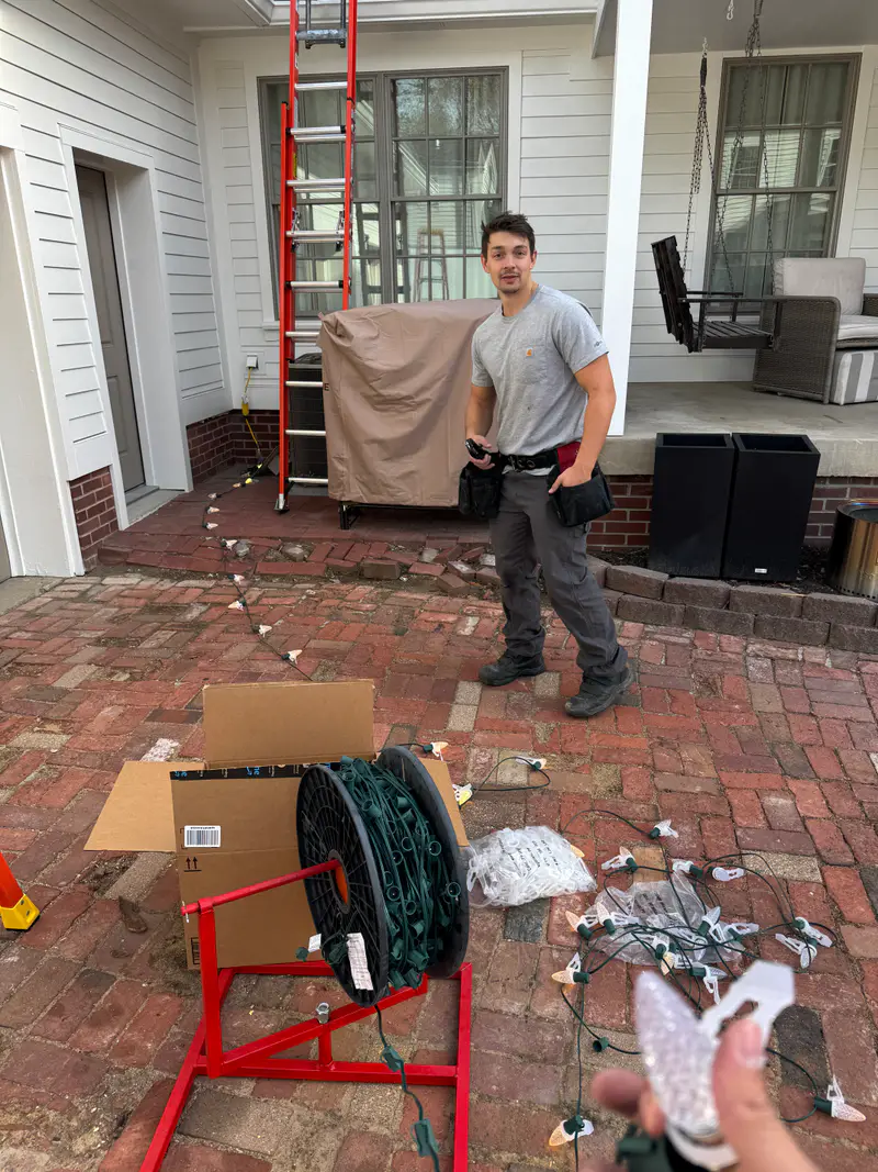 Kyle on a brick patio with a wire reel and boxes of bulbs, getting a job ready